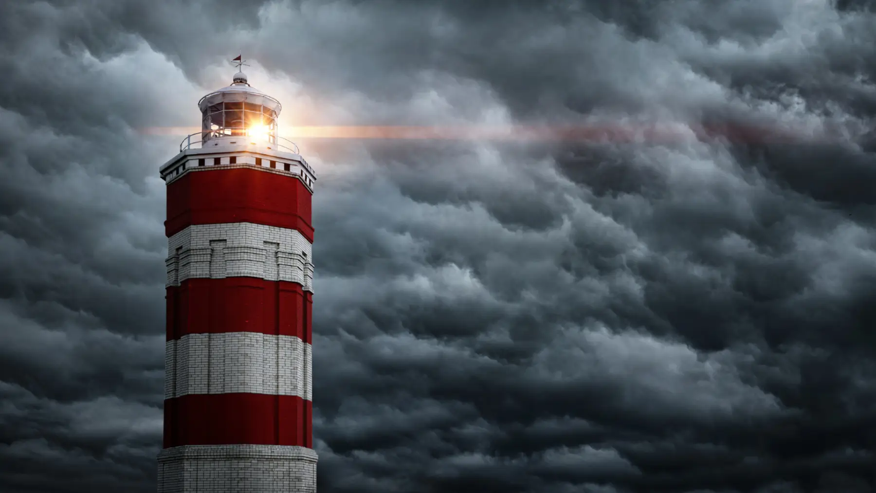 red and white striped lighthouse with light on in front of dark clouds