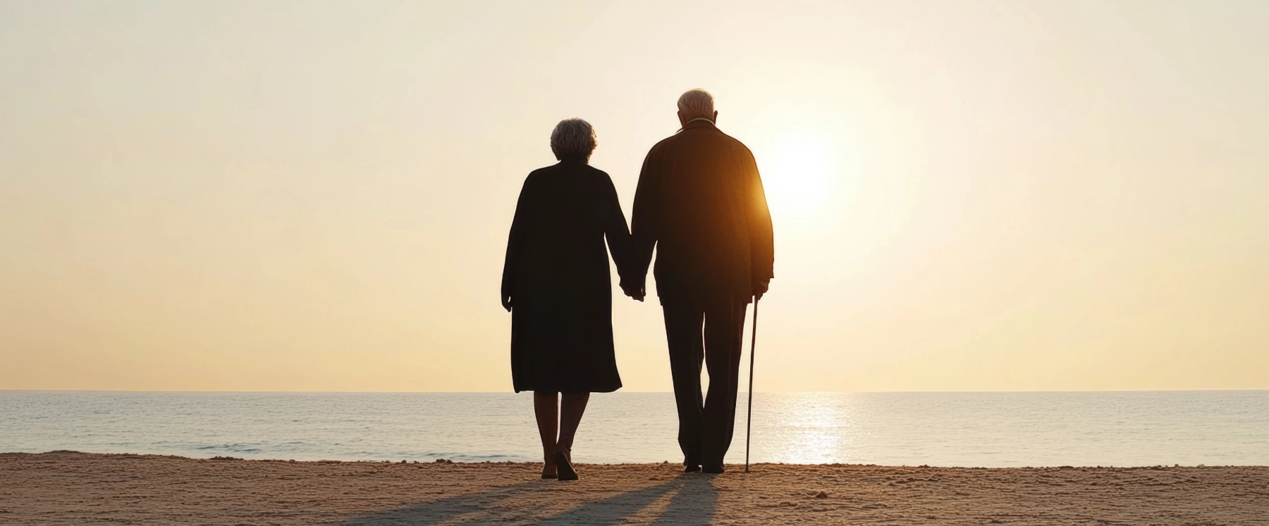 elderly couple holding hands on a beach